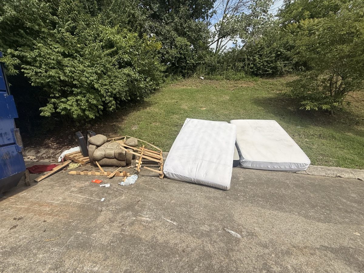 Before: mattresses and broken furniture dumped beside a dumpster, cleared by mattress disposal and junk removal in Middle Tennessee